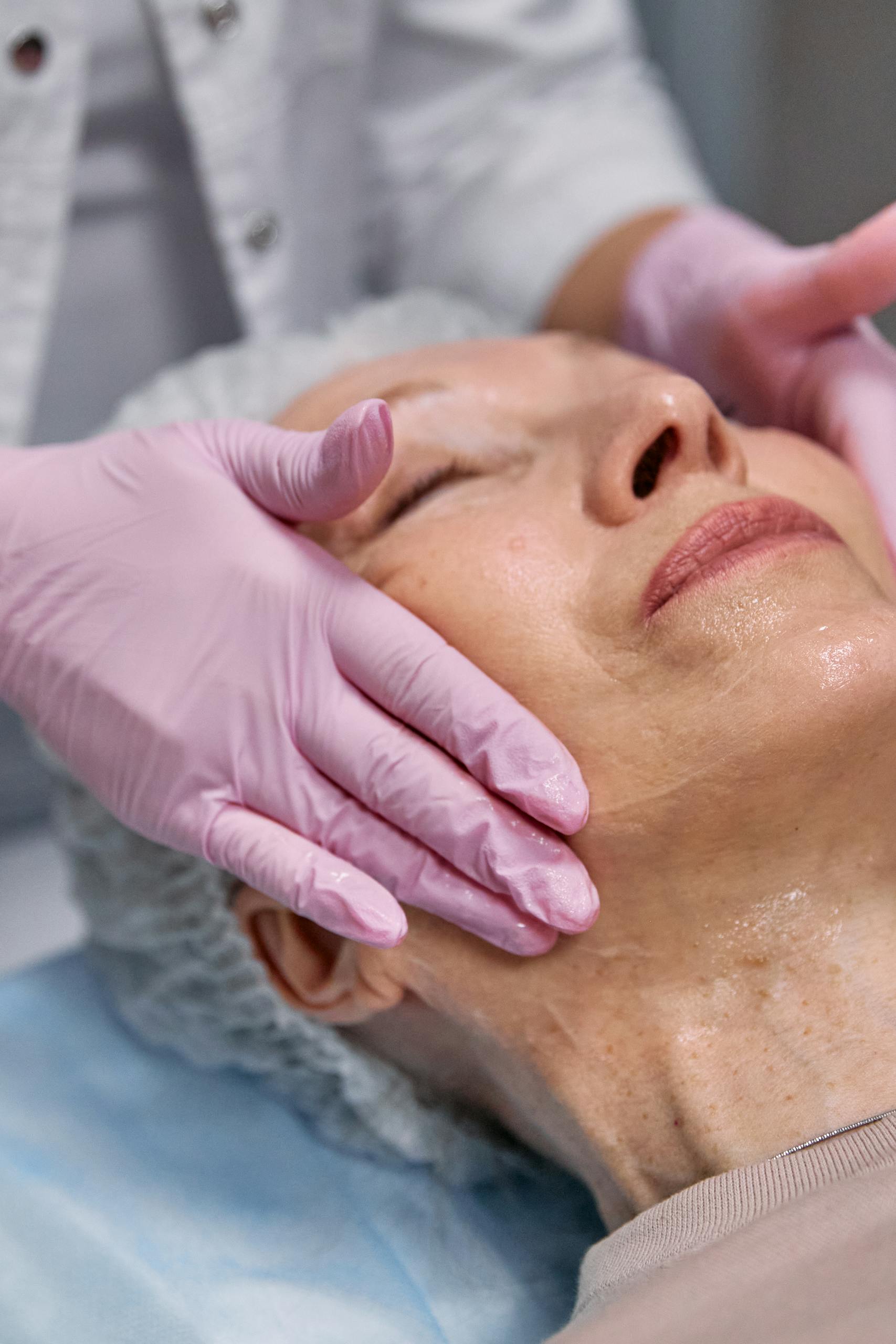 A senior woman enjoys a facial massage at a spa, promoting relaxation and skincare.